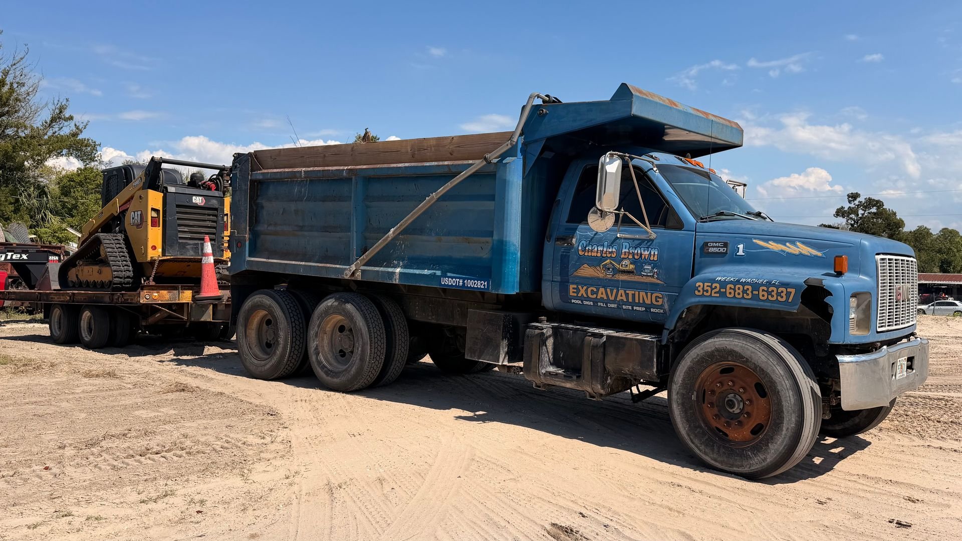 CBE dump truck and CAT loader on active job site — hauling and site prep